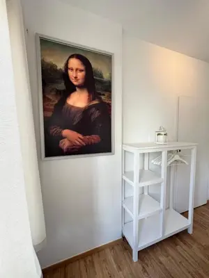 a painting of a woman on a wall next to a shelf at Appartement lumineux dans un quartier animé in Brussels