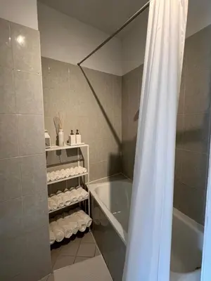 a bathroom with a tub and a shower curtain at Appartement lumineux dans un quartier animé in Brussels
