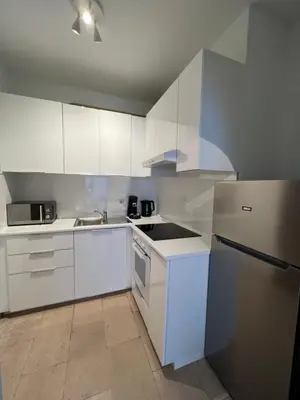 a kitchen with white cabinets and a refrigerator at Appartement lumineux dans un quartier animé in Brussels