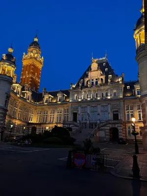 a large building with a clock tower at night at Appartement lumineux dans un quartier animé in Brussels