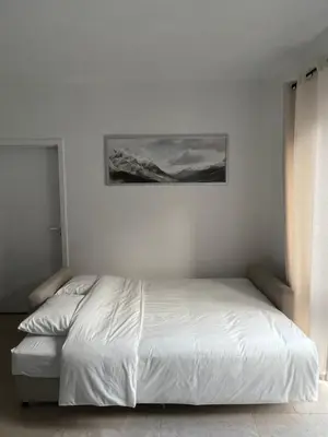 a white bed in a bedroom with a picture on the wall at Appartement lumineux dans un quartier animé in Brussels