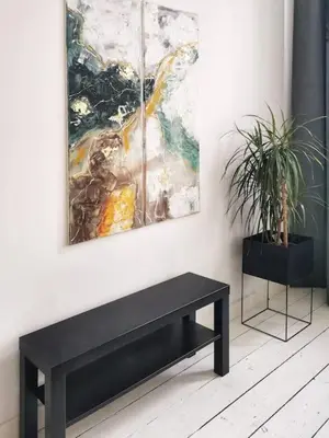 a black bench next to a wall with two paintings at Cosy apartement in Antwerp's hipster neighbourhood in Antwerp