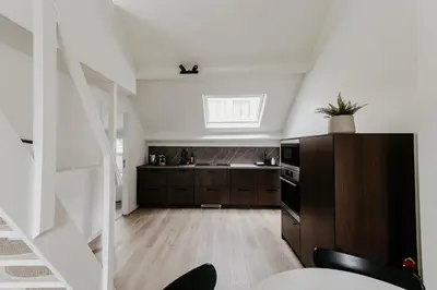 a kitchen with white walls and wooden flooring at Cathedral view from the bathtub in Antwerp