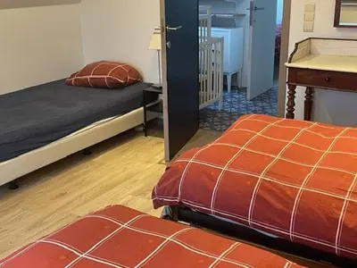 a bedroom with two beds and a table and a desk at Ahwell Guesthouse Gent 5 BR long term in Laarne