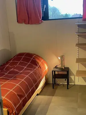 a bedroom with a bed and a table with a lamp at Ahwell Guesthouse Gent 5 BR long term in Laarne