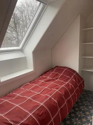 a bed in a attic room with a window at Ahwell Guesthouse Gent 5 BR long term in Laarne