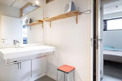 a bathroom with a sink and a stool in it at Ahwell Guesthouse Gent 5 BR long term in Laarne