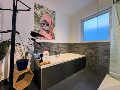 a bathroom with a bath tub and a window at Maison Seigneur in Asse