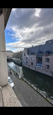a river with buildings and a boat in the water at CES Home in Ghent