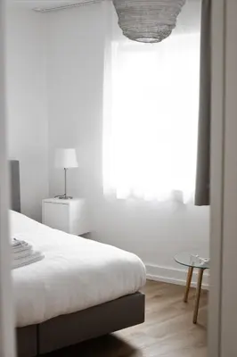 a white bedroom with a bed and a window at FLATS aparthotel in Brussels