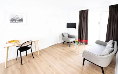 a white living room with a table and chairs at FLATS aparthotel in Brussels