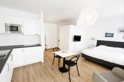 a white bedroom with a bed and a table at FLATS aparthotel in Brussels