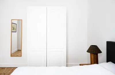 a bedroom with white walls and a bed with a mirror at FLATS aparthotel in Brussels