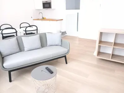 a living room with a couch and a remote control on a table at FLATS aparthotel in Brussels