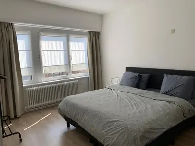 a bedroom with a bed and two windows at Une belle étage à Stockel with charming patio in Brussels