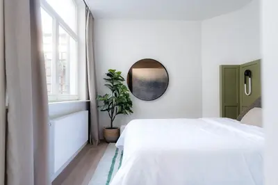 a bedroom with a white bed and a mirror at Cathedral view apartment in Antwerp