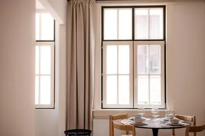 a dining room with a table and three windows at Cathedral view apartment in Antwerp