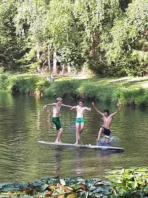 three men are standing on a paddle board in the water at De Vijver in Geel