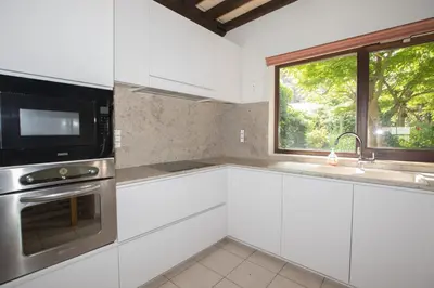 a kitchen with white cabinets and a microwave and a window at De Wijngaard in Ghent