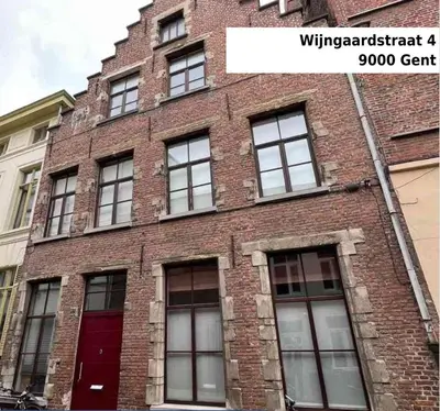 a brick building with windows and a red door at De Wijngaard in Ghent