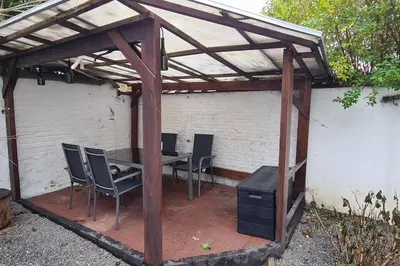 a wooden pergola with chairs and a table and a stove at Magnolia Green Garden New and fully equipped in Brussels