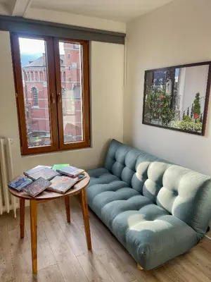 a living room with a blue couch and a table at Stay in Artist’s Gallery in Antwerp
