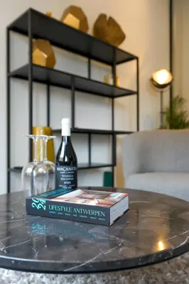 a table with a book and a bottle on a table at Classy 1BR Apartment Overlooking a Beautiful Park in Antwerp