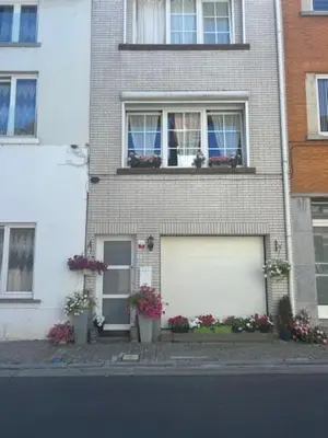 a brick building with two garage doors and flowers at Jungle Magic Room near Atomium , Heyzel Stadium in Strombeek-Bever
