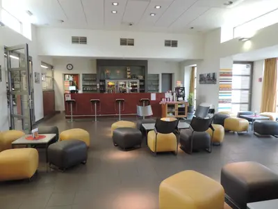a waiting room with chairs and tables and a bar at Hostel Blauwput Leuven in Leuven