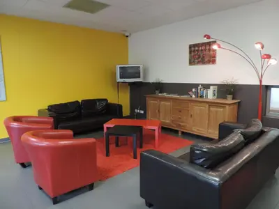 a living room with black and red furniture and a tv at Hostel Blauwput Leuven in Leuven