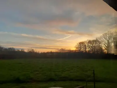 a field of grass with a sunset in the background at Vakantiewoning 't Bruggeneindje in Heist-op-den-Berg