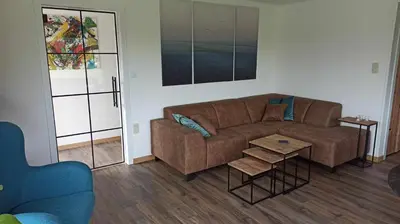 a living room with a brown couch and a table at Vakantiewoning 't Bruggeneindje in Heist-op-den-Berg