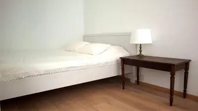 a bed with a table with a lamp on it at Almost White, Near Train, Metro n7688 in Brussels