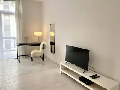 a living room with a television and a white chair at Wit II, Near Metro, Train n7670 in Brussels