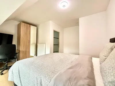 a white bedroom with a bed and a desk at Il Casolare in Beersel