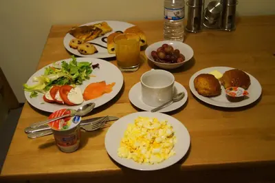 a wooden table with plates of breakfast food on it at EU B&B in Brussels