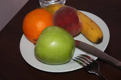 a plate of fruit on a table with a knife and fork at EU B&B in Brussels