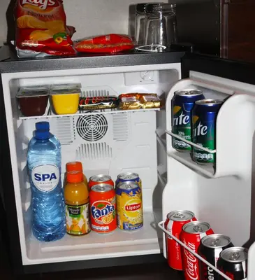 an open refrigerator with drinks and cans of soda at EU B&B in Brussels