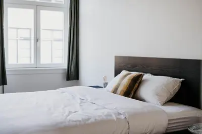 a bedroom with a white bed with a large window at Gorgeous duplex apartment in old city centre in Antwerp