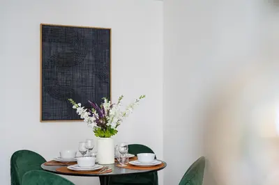 a table with green chairs and a vase with flowers at Modern apartment in the old city center in Antwerp