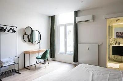 a bedroom with a bed and a chair and a mirror at Modern apartment in the old city center in Antwerp