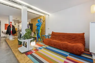 a living room with a orange couch and a colorful rug at Cosy art studio near station with bikes and garden in Ghent