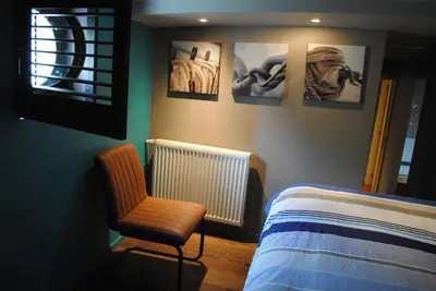 a bedroom with a bed and a chair and pictures on the wall at Boat & Breakfast Bellevue in Ghent