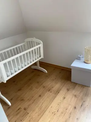 a white crib in a room with a wooden floor at Bubbles and More Guesthouse in Begijnendijk