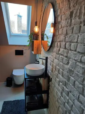 a bathroom with a sink and a mirror on a brick wall at Ateljee Sohie in Hoeilaart