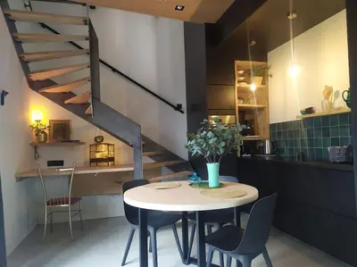 a dining room with a table and chairs and a staircase at Ateljee Sohie in Hoeilaart