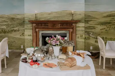 a table with bread and flowers on it with a fireplace at B&B Kasteel Den Tip in Arendonk