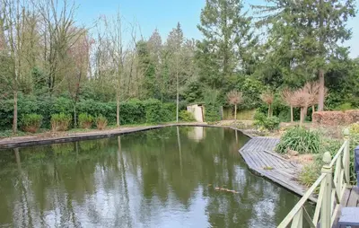 a pond in a garden with a wooden bridge at 2 Bedroom Cozy Home In Arendonk in Arendonk