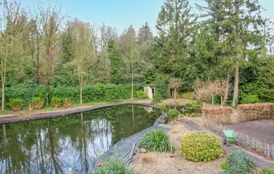 a bridge over a pond in a garden at 2 Bedroom Cozy Home In Arendonk in Arendonk