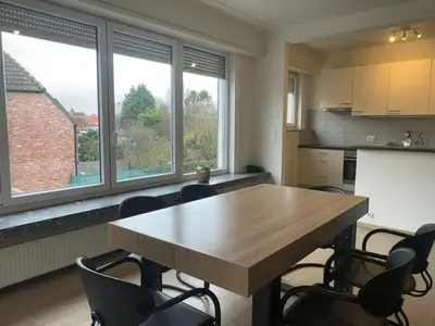 a kitchen with a wooden table and chairs and windows at Spacious Apartment next to Port of Antwerp in Antwerp